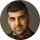 Portrait of a man with short dark hair and a beard, wearing a black shirt against a neutral background.